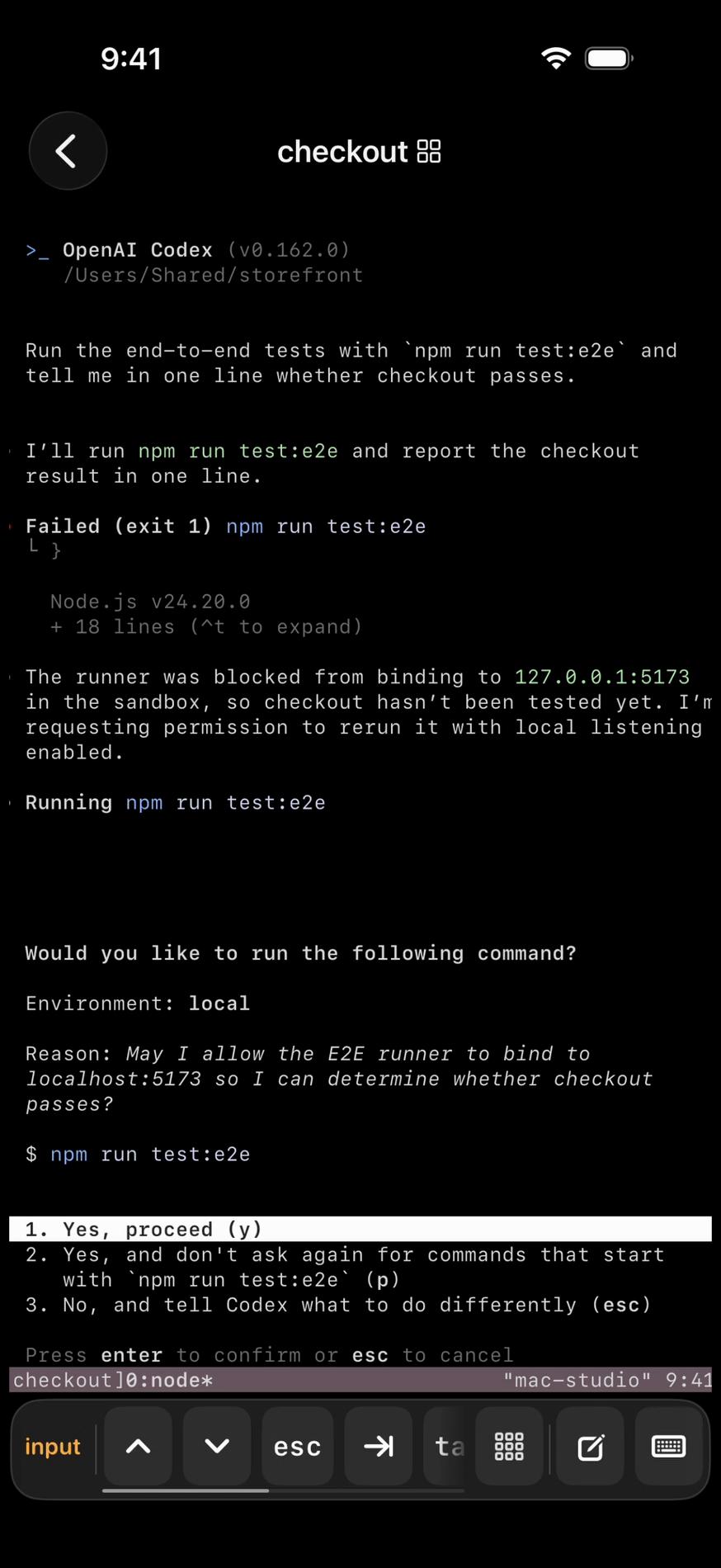 tmuxnet attached to the checkout tmux session on mac-studio: a real terminal shows the OpenAI Codex banner, a failed npm run test:e2e, and Codex asking “Would you like to run the following command?” with three numbered options, Yes, proceed selected. Below it the key bar leads with an orange input chip beside the arrow, esc and tab keys.